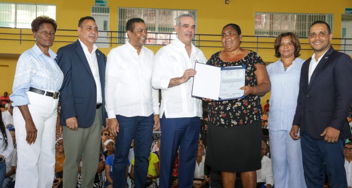 Santo Domingo. – Como parte de su compromiso con la regularización de terrenos y el fortalecimiento de la seguridad jurídica en todo el país, el presidente Luis Abinader, entregó este miércoles una primera partida de 1,400 títulos de propiedad de un total de 3 mil, que beneficiará a 5,600 personas en la provincia Monte Plata, dejando iniciado el programa de titulación municipal a través la Liga Municipal Dominicana. Asimismo, hizo entrega de 500 títulos de propiedad de un total de 1,800 en el municipio de San Antonio de Guerra, donde se beneficiarán a más de 2,000 personas. La entrega de estos títulos en Monte Plata y en el municipio de San Antonio de Guerra, se traduce en beneficio de más de 7,600 personas. En el acto celebrado en el Polideportivo Dr. Fidel Mejía de Monte Plata, donde se entregaron los títulos de propiedad del programa municipal, el jefe de Estado manifestó su alegría con la entrega porque dijo que, ya hoy todos los presentes son propietarios y sus viviendas tendrán un costo mayor por la legalidad que adquieren. 